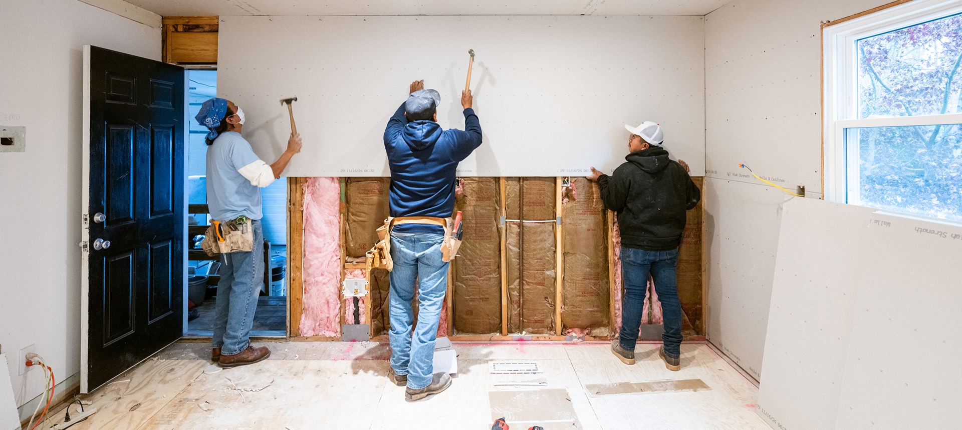 Workers installing drywall in a room