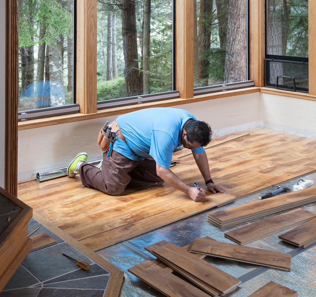 Worker installing wooden floor in sunroom.