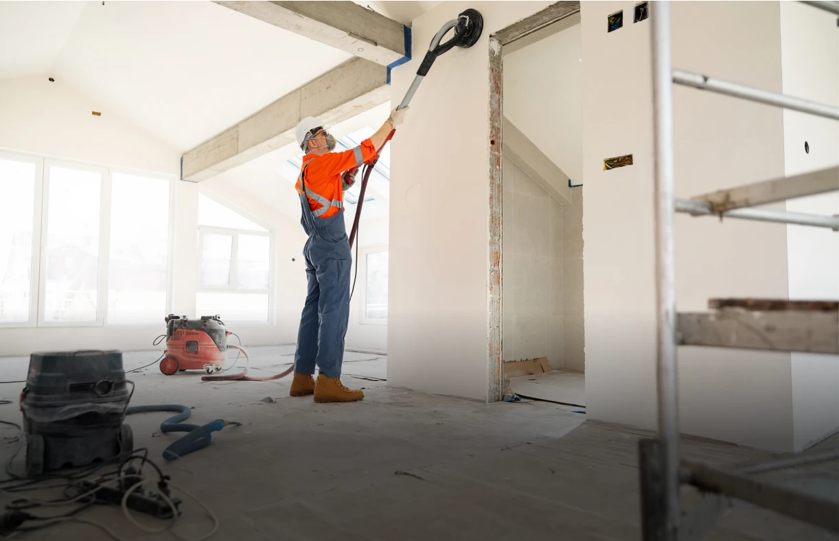 Construction worker using wall sander.